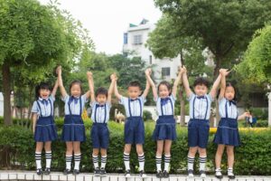 A group of smiling children in uniform holding hands outside, showcasing unity and friendship.