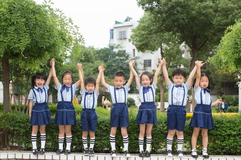 A group of smiling children in uniform holding hands outside, showcasing unity and friendship.