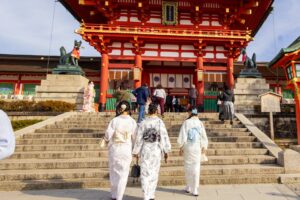 Women in traditional kimono visiting Fushimi Inari Shrine in Kyoto, Japan, during a sunny day.