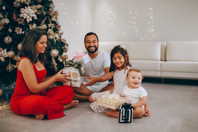 Happy family opening Christmas gifts by the decorated tree indoors.