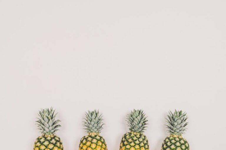 A minimalist image of four pineapples aligned on a white background, perfect for tropical themes.
