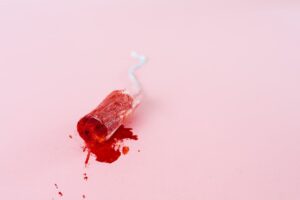 Close-up image of a blood-stained tampon on a pink background symbolizing menstruation.