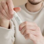 Close-up of a man checking his blood sugar levels using a glucometer indoors.