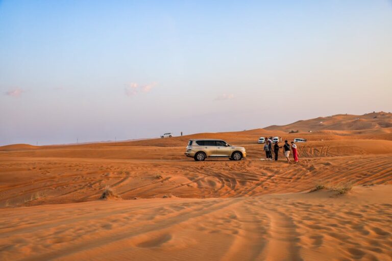 Explore an exhilarating desert safari with SUVs driving over sand dunes at sunset.