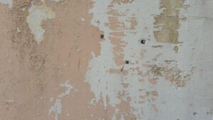 Close-up of a weathered wall with peeling paint revealing underlying layers.