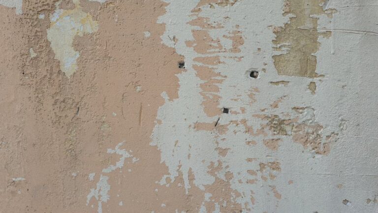 Close-up of a weathered wall with peeling paint revealing underlying layers.