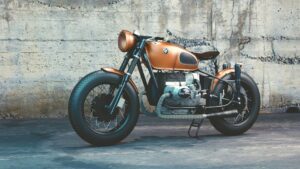 A classic cafe racer motorcycle parked against an industrial backdrop, showcasing its vintage style.