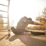 A man stretches in a park wearing activewear, focused on his fitness routine at sunrise.