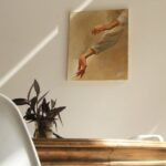 A serene minimalist room featuring a painting, wooden table, and potted plant.