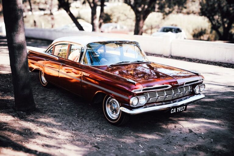 A stunning vintage red classic car captured outdoors in sunlight, highlighting its timeless beauty and elegance.