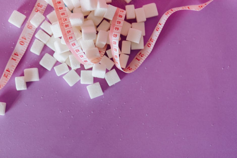 White sugar cubes with a pink tape measure on a purple surface, symbolizing diet awareness.