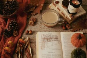 Warm autumn still life with coffee, candles, books, and seasonal decor.