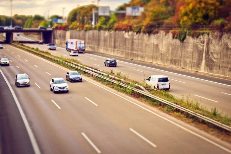 Cars and trucks moving on a highway under sunny skies, showcasing road travel.