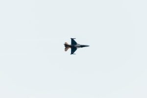 High-altitude jet fighter performing aerial maneuvers against a clear sky backdrop.