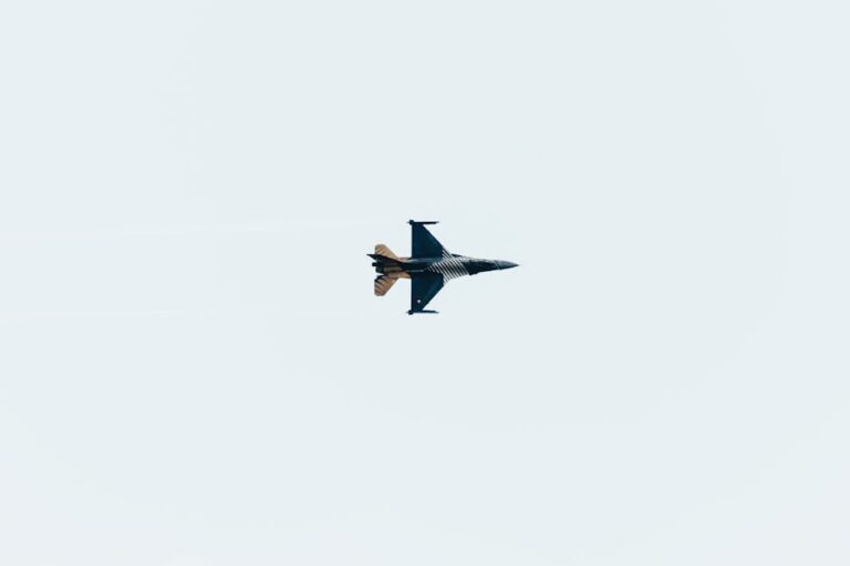 High-altitude jet fighter performing aerial maneuvers against a clear sky backdrop.