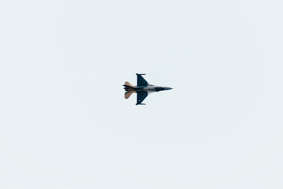 High-altitude jet fighter performing aerial maneuvers against a clear sky backdrop.