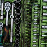 A well-organized set of metal tools in a green toolbox with ratchets and screwdrivers.