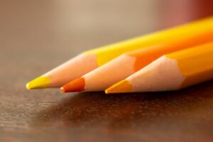 Detailed macro shot of yellow and orange colored pencils on wooden desk.