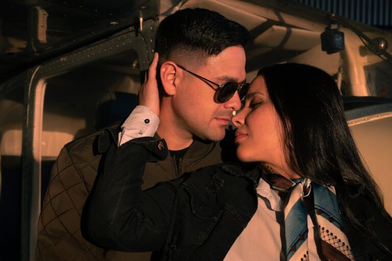 A couple shares a tender moment by an airplane, bathed in sunset light.