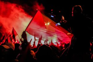 Nighttime protest showcasing vibrant red hues and Palestinian flags, symbolizing solidarity and activism.