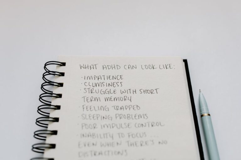 A notebook with handwritten ADHD symptoms like impatience and focus issues.